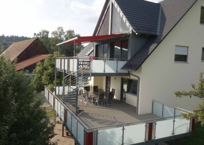 Großer und moderner Balkon mit Balkongeländer aus Stahl und Milchglas von Metallbau Schröder in Schwimbach.
