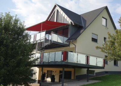 Großer und moderner Balkon mit Balkongeländer aus Stahl und Milchglas von Metallbau Schröder in Schwimbach.