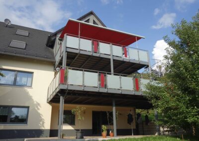 Großer und moderner Balkon mit Balkongeländer aus Stahl und Milchglas von Metallbau Schröder in Schwimbach.