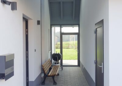 Ein moderner Windfang mit Türe aus Edelstahl von der Firma Metallbau-Schröder in Schwimbach.