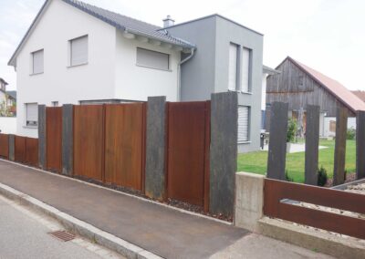 Ein moderner Gartenzaun aus Cortenstahl mit Metallelementen in Thalmässing.
